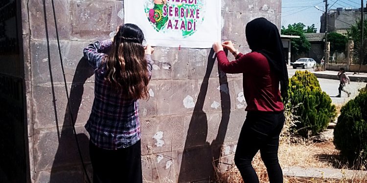 YJC afîşên rengîn “Jin Jiyan Azadî Serbixe Azadî” li kolanên Kobanê