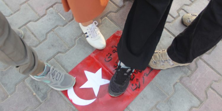 Genç kadınlar, işgalci Türk devletinin bayrağını ayaklar altına aldı